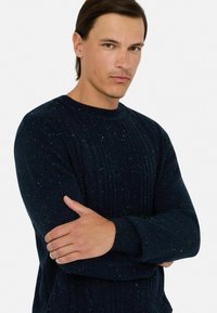 Granatowy sweter z dzianiny z ribbowanym okrągłym dekoltem i teksturowanymi wzorami w warkocz, z wielokolorowymi akcentami w całej tkaninie.