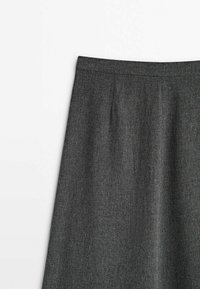 Jupe en laine gris foncé avec taille haute et plis subtils à l'avant, présentée sur un fond blanc uni.