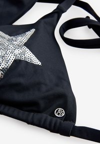 Top de bikini triunghiular din material negru, cu decor de stea din paiete argintii și logo circular mic RSG în colțul din dreapta jos.