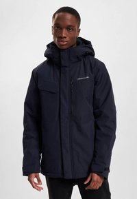 Marineblå vanntett jakke med glidelås foran, hette og flere lommer. Teksturert stoff, avslappet passform og justerbare mansjetter for komfort.