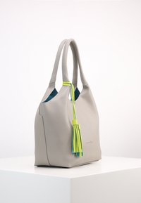 Jasnoszara skórzana torba na ramię o teksturowej powierzchni, z kolorowym akcentem w postaci frędzli w zielonym i niebieskim kolorze oraz kontrastującym, turkusowym wnętrzem.