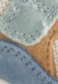 Zapatilla con una parte superior de múltiples texturas que combina acentos de ante en verde, beige y azul, superposiciones de malla y detalles de costuras en contraste.