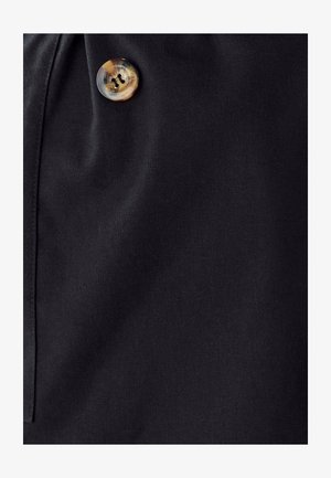 Zwarte stof met een gladde textuur, voorzien van een ronde gemarmerde knop. Close-up detail toont de twee gaatjes en de stiksels van de knop.