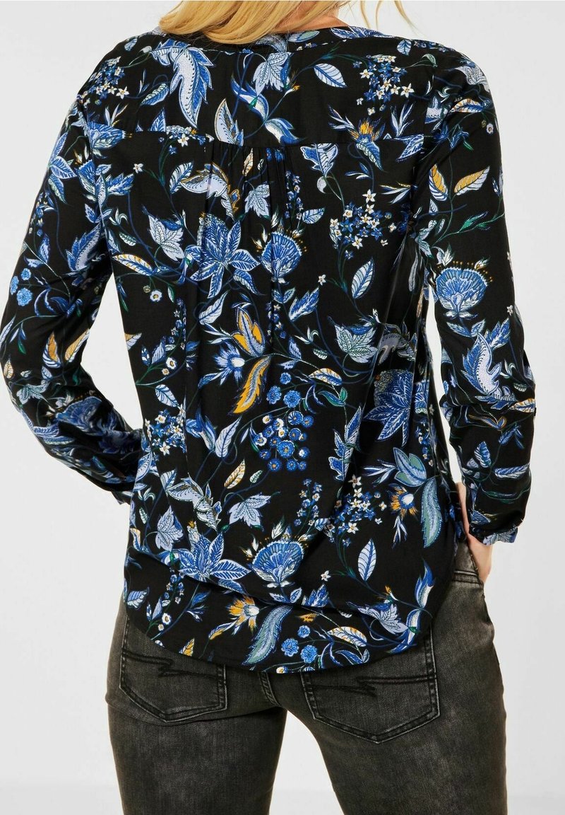 Blusa nera con motivi floreali blu e gialli, maniche lunghe e design con pieghe sul retro. Realizzata in tessuto leggero, dalla morbida texture.