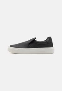 Mustamugavad slip-on tennisjalatsid sileda nahast ülaosaga, tekstuursete mustade aktsentidega kannal ja valge kummist tallaga. Lihtne disain, ilma paeladeta.