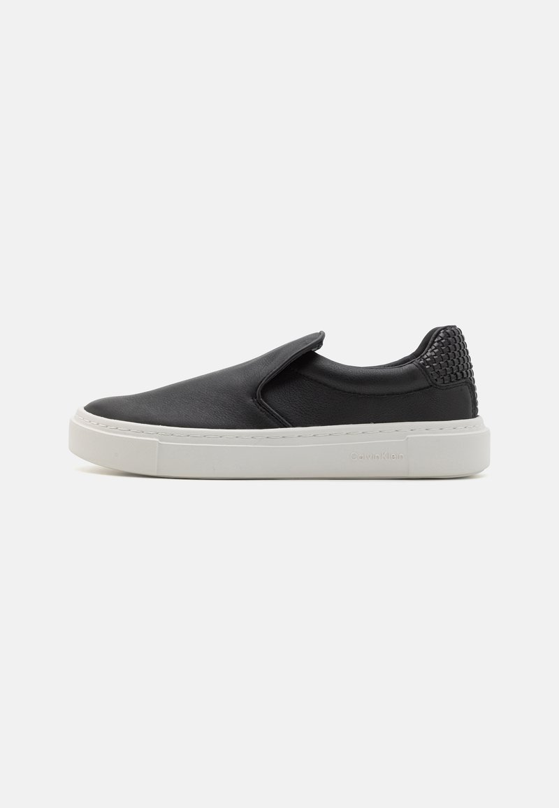 Mustamugavad slip-on tennisjalatsid sileda nahast ülaosaga, tekstuursete mustade aktsentidega kannal ja valge kummist tallaga. Lihtne disain, ilma paeladeta.