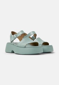 Mint green leather sandals with cross-strap design, open toe, and a thick sole. Features a buckle closure and textured insole for comfort.