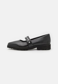 Zapato plano Mary Jane de cuero negro con punta redondeada, suela gruesa y una correa al tobillo que presenta acentos de tachuelas plateadas.