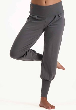 Graue, enganliegende Jogginghosen mit einem breiten, elastischen Bund, gesammelten Bündchen und Seitentaschen, aus einem weichen, dehnbaren Stoff gefertigt.