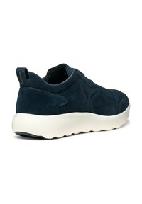 Zapatilla de ante azul marino con puntera redondeada, suela blanca hundida y parte superior texturizada. Cuenta con una lengüeta en la parte trasera para facilitar el calzado.