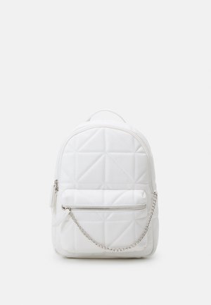 Lille hvid quiltet rygsæk med en lynlåslomme foran og en sølvfarvet kædedetalje mod en ensfarvet baggrund.