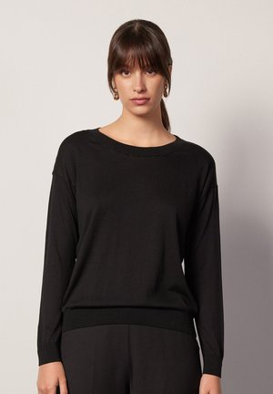 Maglione nero a maniche lunghe con scollatura rotonda e polsini a coste, realizzato in un tessuto liscio. Presenta una vestibilità comoda e un design minimalista.