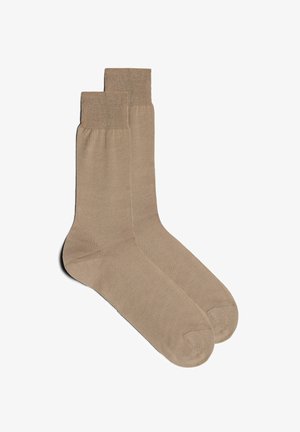 Beige Baumwollsocken mit geripptem Bund, glatter Oberfläche und verstärkter Spitze. Klassische Knöchellänge, entworfen für Komfort und Langlebigkeit.