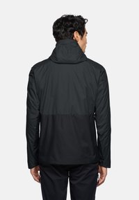 Veste noire imperméable avec un col haut, des poches zippées et un design bi-couleur avec une texture mate. Convient pour une utilisation en extérieur.