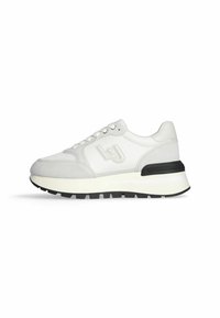 Sneaker bianca con tomaia in mesh e suede, caratterizzata da una suola nera, un'intersuola bianca e dettagli del logo discreti sul lato.