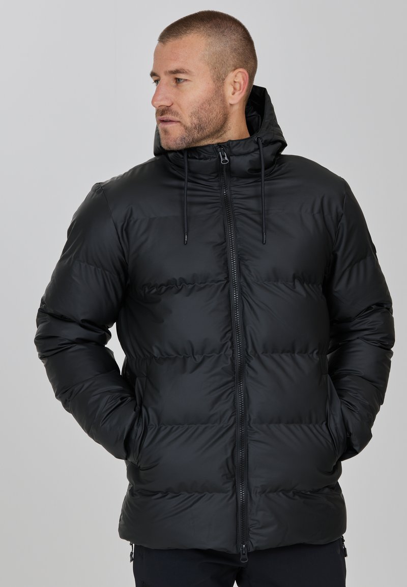 Sort pufferjakke med hætte, der har en slank, skinnende overflade, kviltet mønster, frontlynlås og justerbare snore ved halsen.