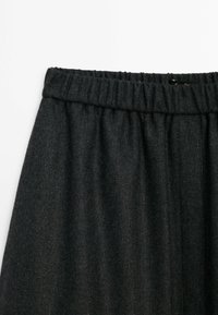 Jupe à taille élastique gris foncé en tissu texturé, présentant des plis doux et une finition lisse. Aucun motif ni élément métallique visible.