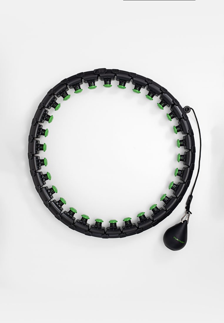 Zwarte cirkelvormige fitnesshoepel met groene accenten, gemaakt van plastic, met een gewogen bal die aan een koord is bevestigd. Elk segment heeft een unieke vorm.