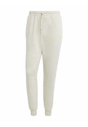 Pantaloni tuta color beige chiaro realizzati in un tessuto morbido, dotati di una vita elasticizzata con cordino, gambe affusolate e polsini in costina.