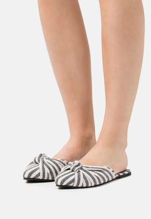 Chaussures à enfiler avec un détail de nœud, dotées d'un motif rayé noir et blanc, en tissu doux et avec une semelle plate.