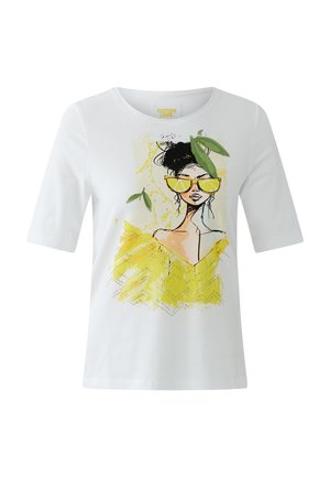 Chemise blanche à manches courtes avec illustration d'une femme portant des lunettes de soleil jaunes, un haut jaune épaules dénudées et des feuilles vertes autour de sa tête.