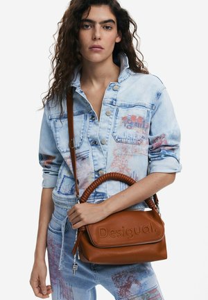 Borsa in pelle marrone con manico intrecciato e logo "Desigual" impresso, abbinata a un giubbotto di jeans azzurro chiaro e jeans a motivi.