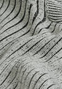 Tissu tricoté texturé en gris clair avec des rayures noires verticales ; matériau doux avec un motif en vagues et un subtil éclat.