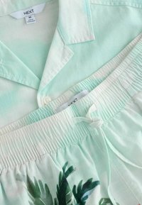 Ensemble de pyjama vert clair avec haut boutonné à col et short à taille élastique avec imprimé feuille verte tropicale.