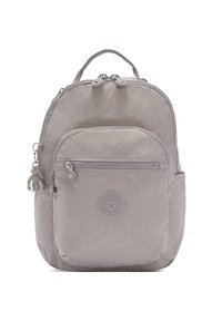 Mochila gris claro hecha de tela texturizada, con forma redondeada, cierre con cremallera, bolsillo frontal y un llavero decorativo en forma de mono.