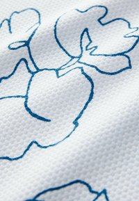 Material alb cu o suprafață texturată, având un design floral albastru. Modelul include contururi îndrăznețe ale petalelor și frunzelor.