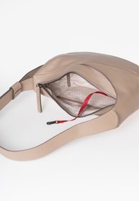 Borsa a tracolla in pelle beige con scomparto principale con cerniera, rifinitura in tessuto leggero a fantasia e tracolla rossa con clip nera interna.