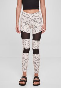 Leggings med blomsterdesign i krem og svart, med gjennomsiktige svarte nettpaneler på lårene. Glatt stoff, tettsittende design.