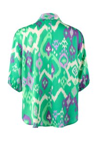 Koszula z krótkim rękawem, zapinana na guziki, wykonana z zielonej tkaniny z białym i fioletowym wzorem ikat. Posiada kołnierzyk i luźny krój.