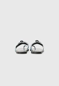 Black back view of flat sandals featuring a denim strap with frayed edges and a textured footbed, suitable for casual wear.