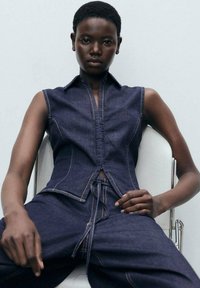 Denim mouwloze top met een aansluitend ontwerp, donkerblauwe kleur, puntige kraag en gesloten middenknopen, gecombineerd met bijpassende broek.