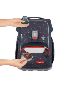 Marineblauer Rucksack mit roten und grauen dreieckigen Mustern, Front-Reißverschlussfach, individuell gestaltbaren Aufnähern und einem sicheren Verschluss oben.