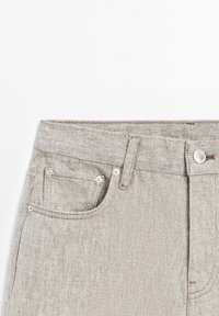 Hellgraue Denim-Jeans mit klassischem Fünf-Taschen-Design, Metallnieten und einem Reißverschluss. Köperstruktur und sichtbare Nähte.