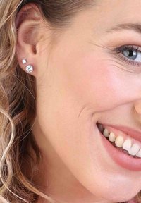 Boucles d'oreilles en argent ornées de deux pierres précieuses claires, l'une plus grande et l'autre plus petite, dans un design simple et épuré.