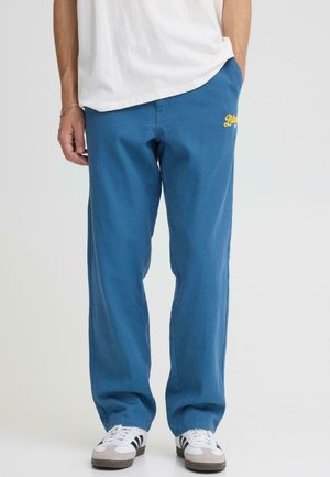 Pantaloni da jogging blu realizzati in tessuto strutturato con vestibilità rilassata. Presentano un logo ricamato giallo sulla coscia sinistra e tasche laterali.