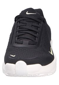 Baskets noires en tissu structuré, avec un logo Nike blanc, des lacets ronds et une semelle blanche contrastante.