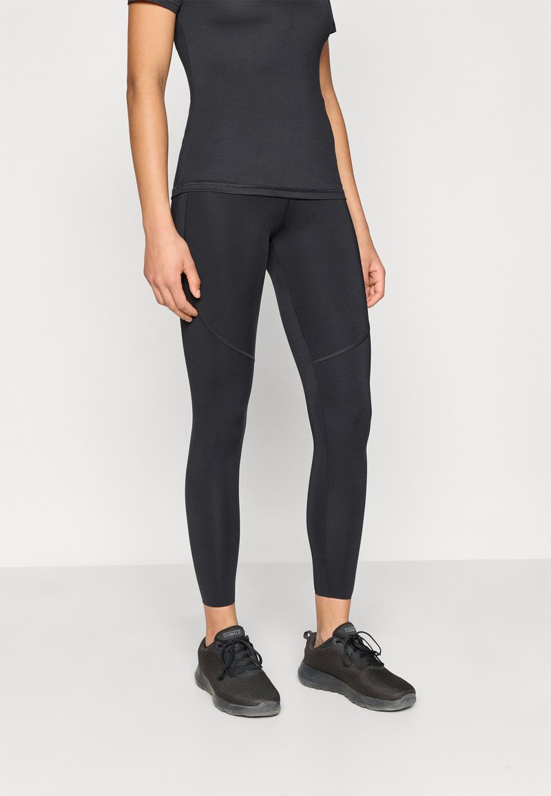 Μαύρο αθλητικό κολάν και εφαρμοστή μπλούζα με κοντά μανίκια. Το κολάν έχει λεία υφή με διακριτικές ραφές. Φοριέται με μαύρα αθλητικά παπούτσια.