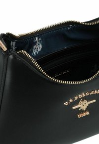 Borsa in pelle nera con cerniera e accessori dorati. Interno foderato in tessuto blu navy con un motivo sottile. Logo ben visibile.