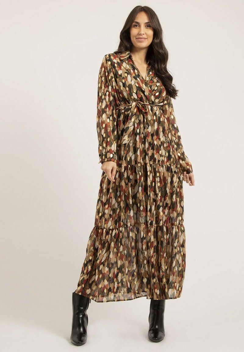 Robe longue à motifs dans des tons terreux avec un col, une taille ceinturée et une jupe à volants. Fabriquée en matériau léger et fluide. Bottines noires à la cheville.