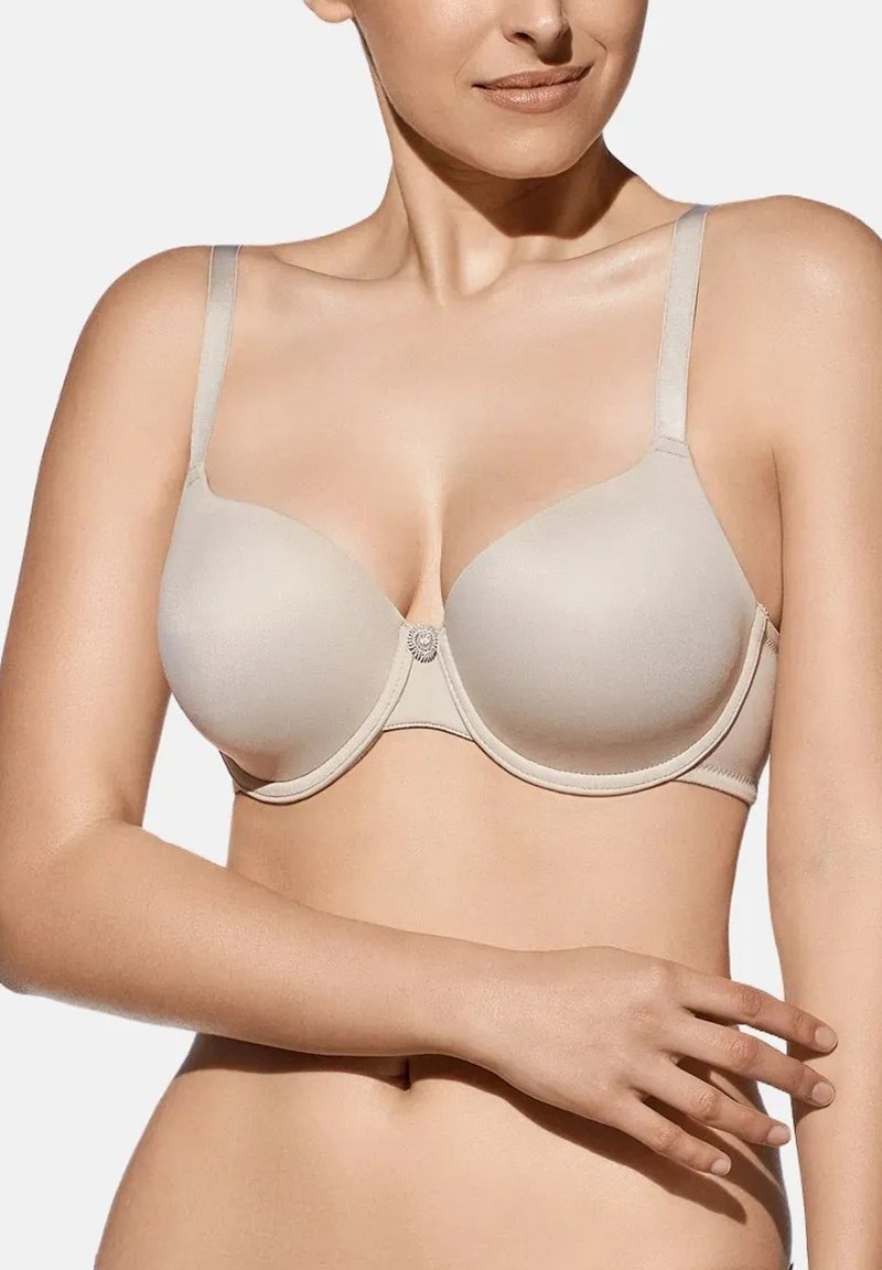 Sostén acolchado beige con construcción sin costuras, tirantes ajustables y un punto decorativo en el centro. Textura suave y diseño que brinda soporte.