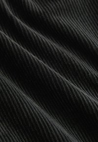 Tissu en velours côtelé noir avec des nervures verticales prononcées, affichant une texture douce et une couleur profonde. Surface lisse avec un léger éclat.