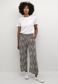 Pantalons larges à motif noir et blanc avec une taille élastique, associés à un t-shirt blanc uni et des baskets blanches.