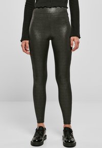 Leggings s visokim strukom, s efektom sjaja u tamnosivoj boji s glatkom teksturom, upareni sa sjajnim crnim cipelama, prikazujući elegantnu siluetu.