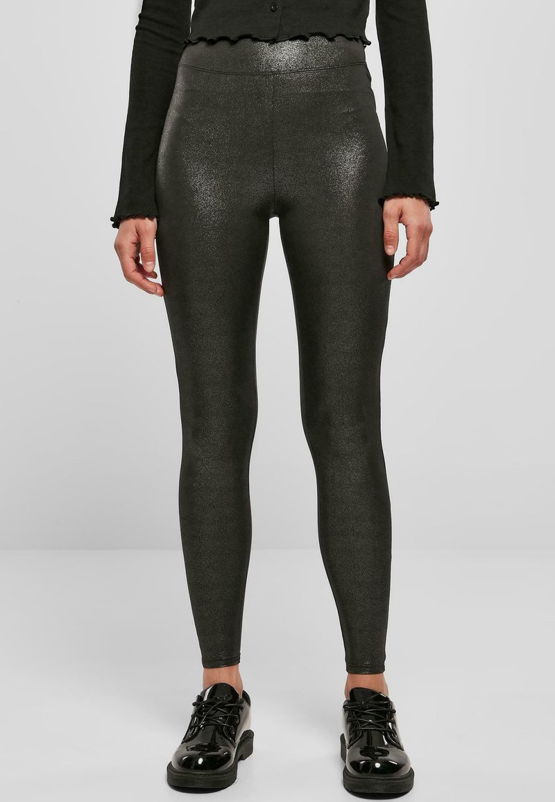 Leggings s visokim strukom, s efektom sjaja u tamnosivoj boji s glatkom teksturom, upareni sa sjajnim crnim cipelama, prikazujući elegantnu siluetu.