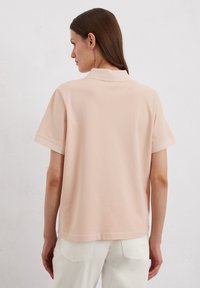 Lichtroze polo T-shirt met korte mouwen, gemaakt van zachte stof, met een klassieke kraag en een relaxte pasvorm met een rechte zoom.