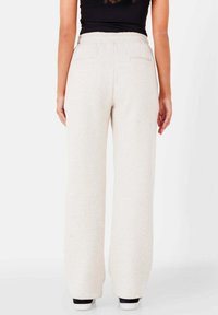 Hellbeige Sweatpants mit lockerer Passform, elastischem Bund und zwei Gesäßtaschen. Das Material wirkt weich mit einer glatten Textur.